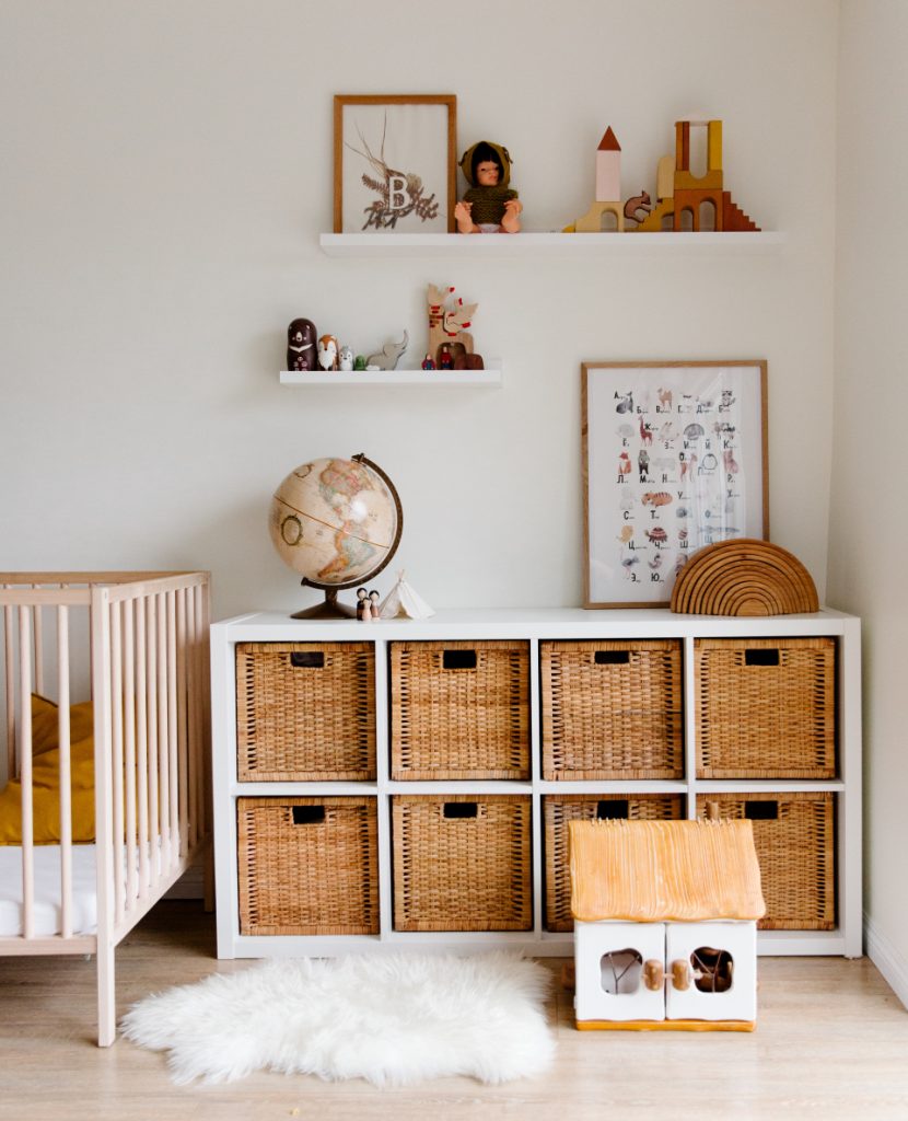 Chambre d'enfant avec espace de rangement en osier, un lit à barreaux et des jeux en bois